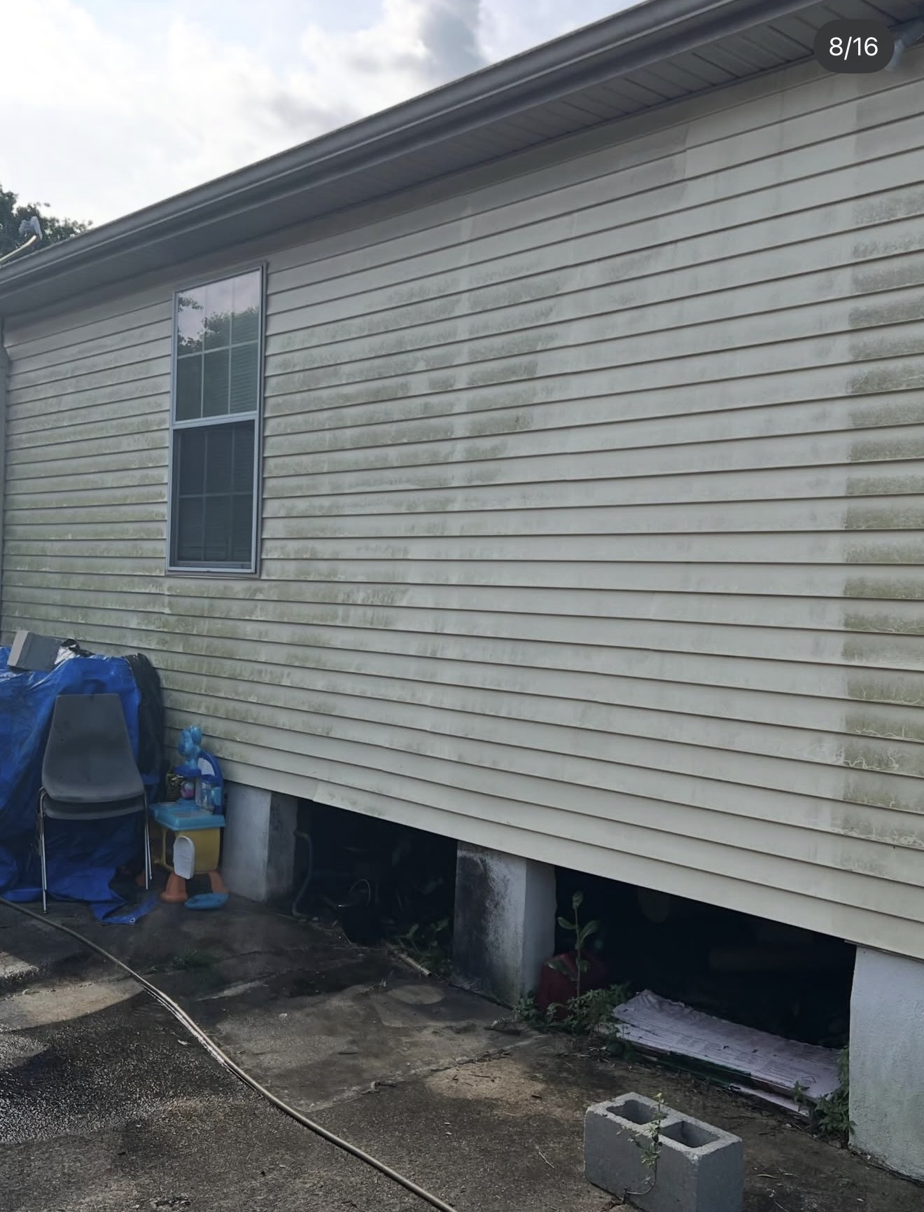 Home siding covered in green mildew streaks before pressure washing